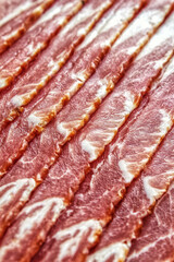 Raw bacon, slices of fresh smoked bacon lying obliquely.
