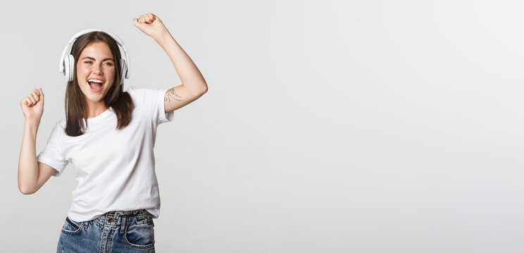 Attractive Joyful Girl Dancing In Wireless Headphones, Listening Music