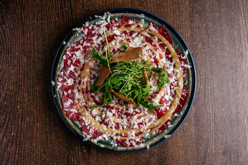 marble beef carpaccio with sauce and herbs