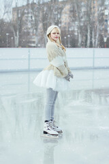 Bright color photo of a girl skater skating at an outdoor city skating rink in winter with a toy...