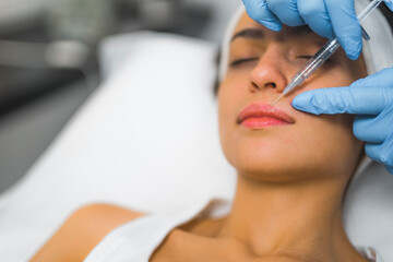 Extreme closeup indoor shot showing lip filler procedure at SPA and wellness salon. A licensed healthcare professional performing dermal filler on her caucasian female patient. High quality photo