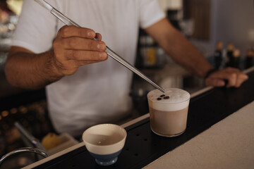 Barista preparing coffee making foam with the spoon.
