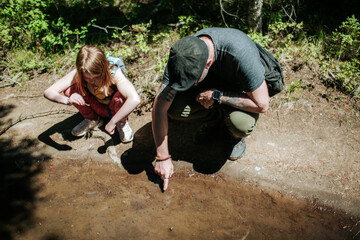 dad showing daughter tadpoles on a hike on a sunny day