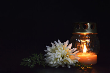 Condolence card. Burning candle and white chrisanthemum on dark background with copy space