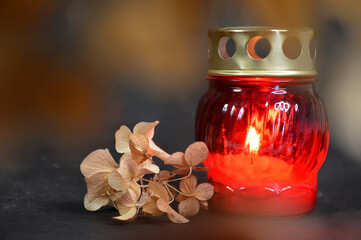  Sympathy card. Burning candle and dry hydrangea flower on dark background.