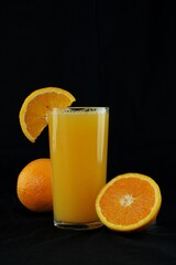 Glass of orange juice on black background