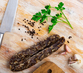 Popular Spanish sausage cured pork on a wooden table with garlic, peppercorns and a sprig of fresh greenery