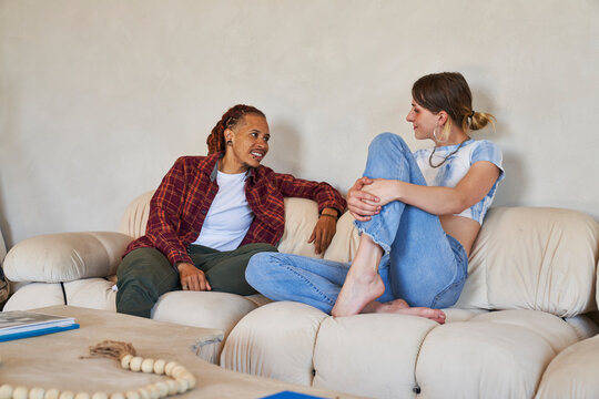 couple talking on sofa with legs on seat smiling