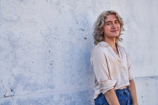 person posing in front of concrete wall in shade angled shot
