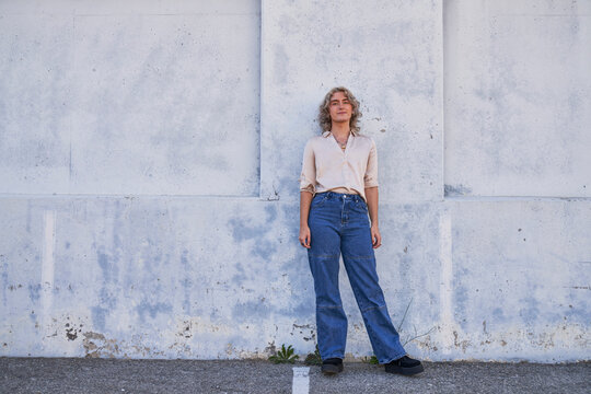 person posing in front of concrete wall in shade wide shot