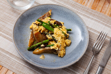 Scrambled eggs with forest mushrooms and asparagus on plate, healthy breakfast