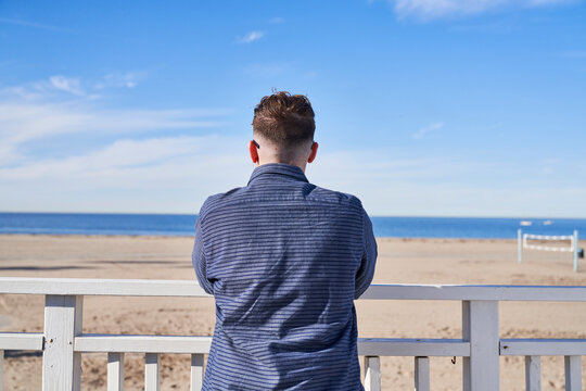 person standing facing beach