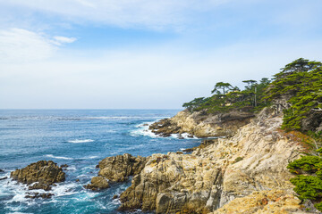 Fototapeta na wymiar Monterey Bay, California. Rocky coastline, cypress trees, Pacific Ocean, and beautiful cloudy sky