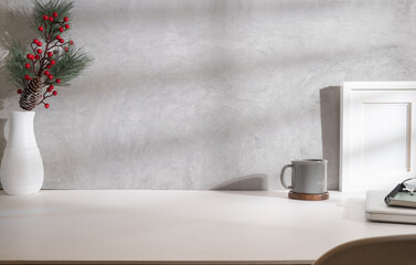 Minimal workplace with blank picture frame, coffee cup and fir tree branches in vase on white table.