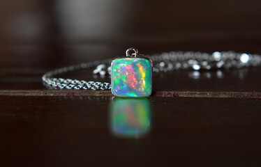 Opal is an opal pendant necklace placed on the ground.