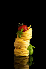 Ingredients of Italian pasta with basil and tomato on a black background. Close-up