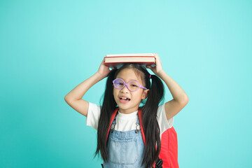 Portrait of happy lazy little girl covering head with book and smiling to camera.