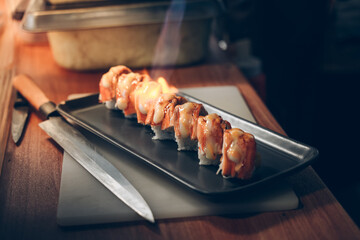 sushi salmon burn is a meal fish. chef is cooking by fire burn. sushi is a street food of japan and...