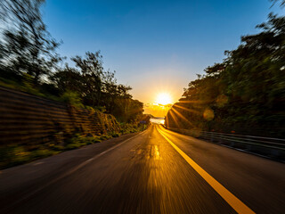 POV shot of driving through the woods and up a slope along the coast at dawn
