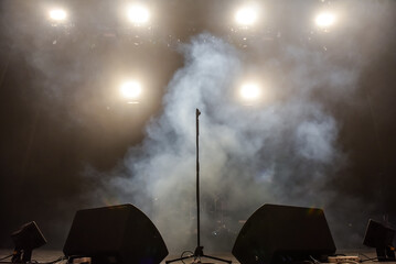 microphone on a stand with stage smoke and light