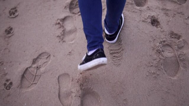 Tracking slow motion shot of someone leaving footprints in the sand