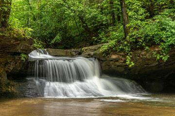 Fototapeta na wymiar Waterfall over rock in a green forest