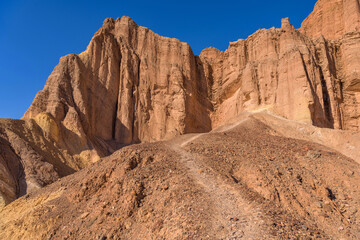 Fototapeta premium Red Cathedral - A rocky trail winding towards steep cliffs of Red Cathedral, Death Valley National Park, California, USA.