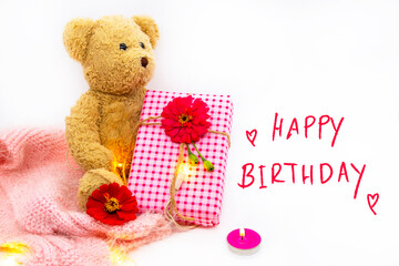 happy birthday message card handwriting with gift box, teddy bear and knitting wool scarf in winter season arrangement flat lay postcard style on background white