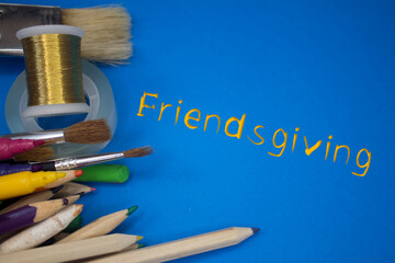 Overhead shot of school supplies with Friendsgiving text. Brushes, pencils, artistic tools. Art And Craft Work Tools.