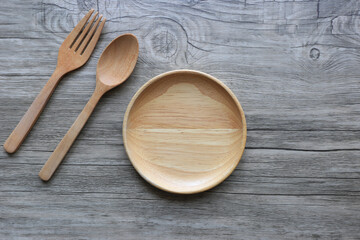 Wooden bowl with spoon and fork on wooden background