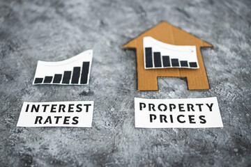 interest rates increasing and property prices dropping, interest graph next to cardboard house with stats going in opposite directions