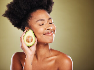 Face, skincare and black woman with avocado for health, wellness and nutrition on green background....