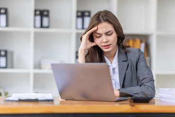 Young business Asian woman stressed while working, Tired asian businesswoman with headache at home office, payment stressed and confused by calculate expense from invoice or bill tax.

