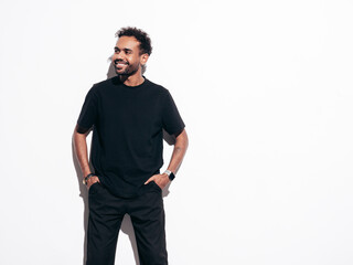 Fototapeta premium Handsome confident hipster model. Sexy unshaven man dressed in summer t-shirt and jeans clothes. Fashion male posing near white wall in studio at sunny day. Isolated