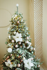 Close up view of Christmas tree branch with decorative balls, white flowers, toys and shining garland. Christmas tree branches with balls. winter holidays