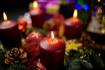 Shallow focus advent wreath with four lit candles and pine cones