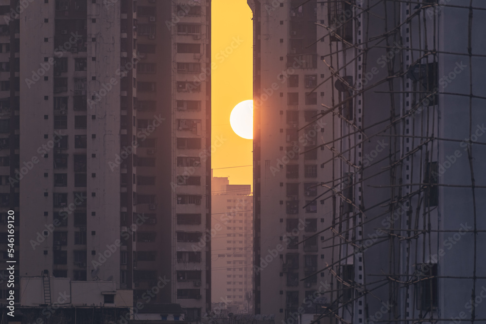 Wall mural Sun setting behind a high rise skyscraper in the city of Mumbai.