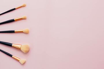 Makeup brushes and sponges used to apply makeup flat lay with space for words on pink background
