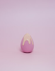 Makeup liquid foundation pouring on make-up blender sponge, closeup. Applying Foundation beauty facial cosmetics, tool for perfect make up. Dripping bb cream or concealer, over pink background