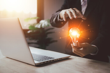 Businessman hand hold virtual lightbulb with laptop (notebook). New ideas inspiration and innovation technology concept. Science and communication concept.