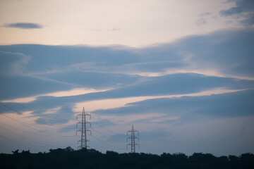 Beautiful Cirrostratus clouds in the sky above electric power pylons on the hills of the Borivali National Park.