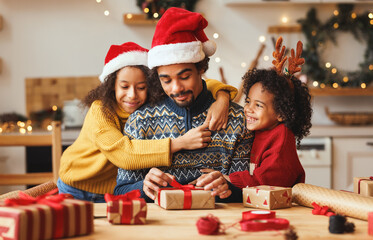 Happy ethnic family father and children pack Christmas gifts