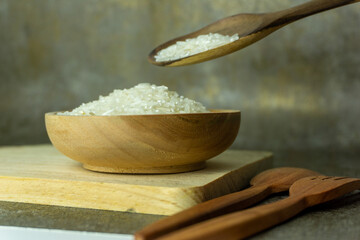uncooked rice or dry rice. raw rice in wooden bowl with wooden spoon and fork