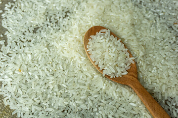 dry rice or uncooked rice. top angle view of raw rice and wooden spoon