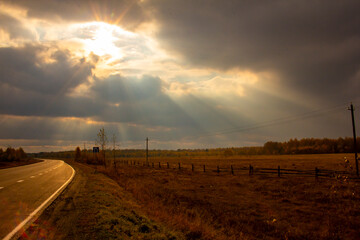 The road at sunset in the rural hinterland. Evening on the side of the road in the fields.