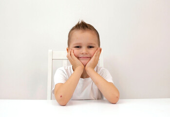 Laughing boy close-up on a white background. A happy child looks into the camera and smiles.