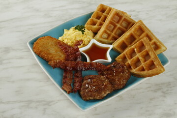 Breakfast platter with bacon, hash brown, beef burger patty, scrambled egg and waffles