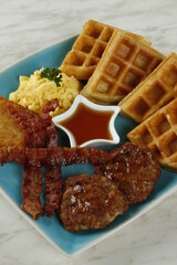 Breakfast platter with bacon, hash brown, beef burger patty, scrambled egg and waffles
