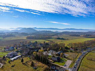 Aerial view of charming small town in Poland. Mountains with fall multicolor trees and beaufitul sky.