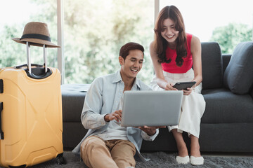 Travel concept, Happy Asian young couple using a laptop and booking hotel online, preparing to travel